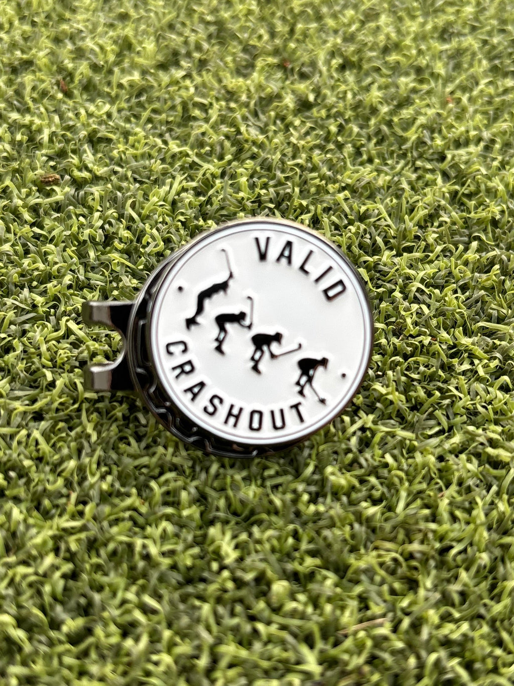 A round metal golf ball marker and hat clip with a white face and black graphics, featuring the text 'VALID CRASHOUT' from Big Max viral Instagram golf video. 